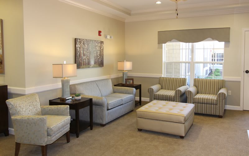 A cozy and well-lit living room with sofas, chairs, and a large window.