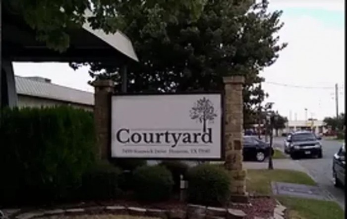 An outdoor sign for Courtyard hotel on a landscaped area.