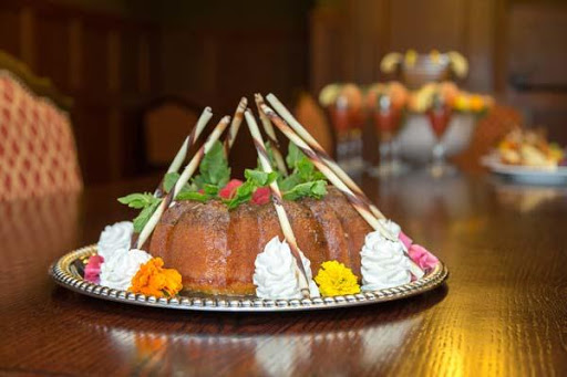 A beautifully decorated dessert featuring a cake with chocolate sticks and fresh mint, served on an elegant platter.