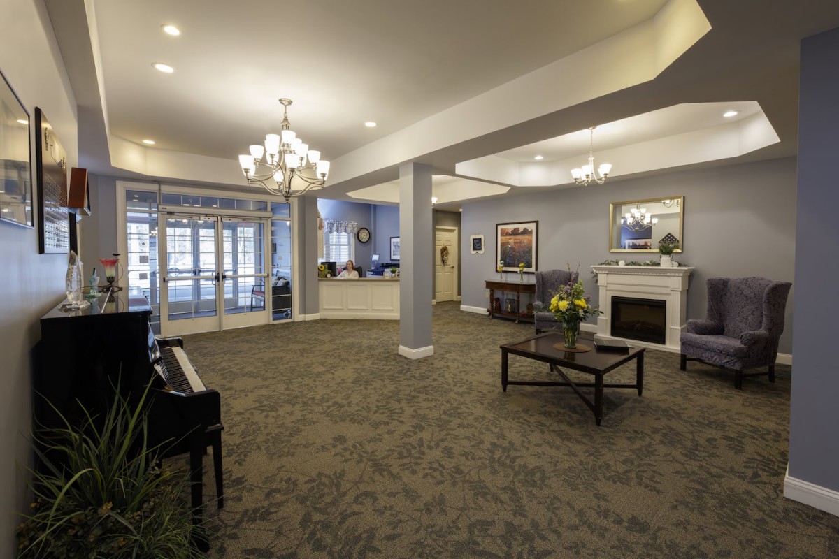 A spacious and elegantly decorated lobby featuring a chandelier, piano, and fireplace.