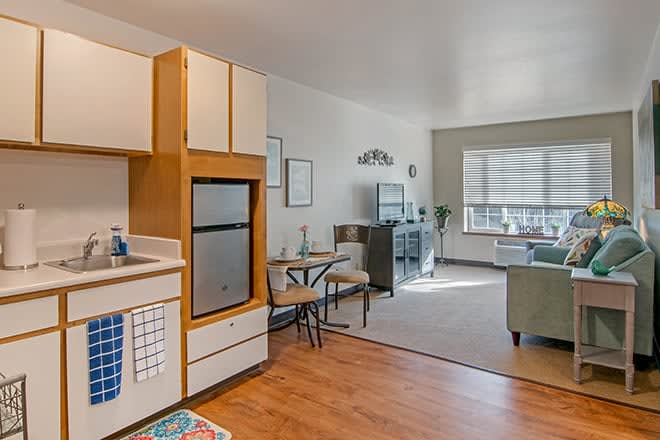 A cozy open-plan apartment featuring a compact kitchen and a living area with a dining table.