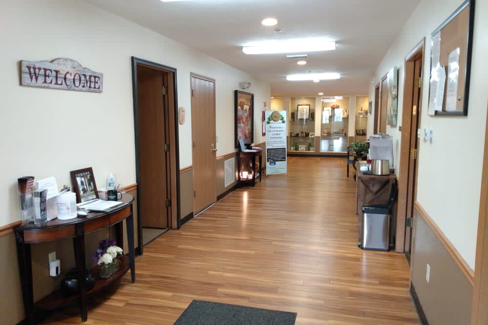 A well-lit hallway with wood flooring, featuring office decor and furniture.