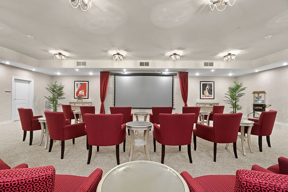 A stylish home theater with red chairs and a large screen.