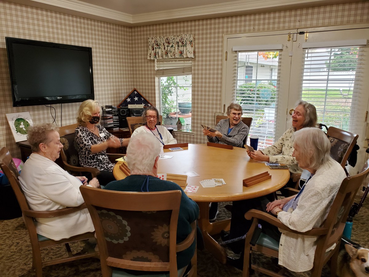 A group of seniors gathered around a round table for a meeting indoors.