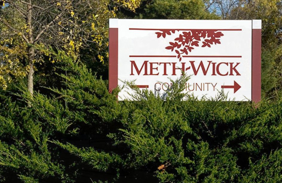 A community sign partially obscured by foliage.
