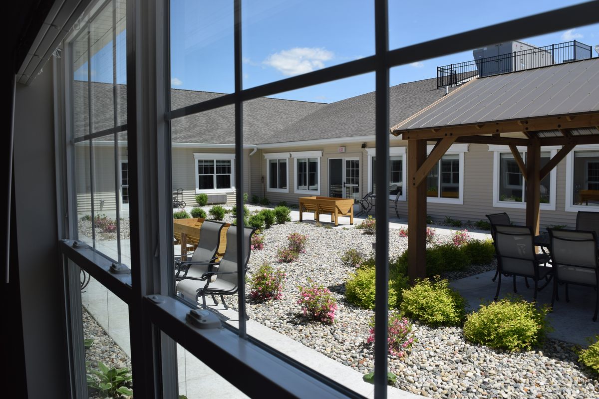 View of a well-maintained courtyard with outdoor seating, captured from inside through a window.