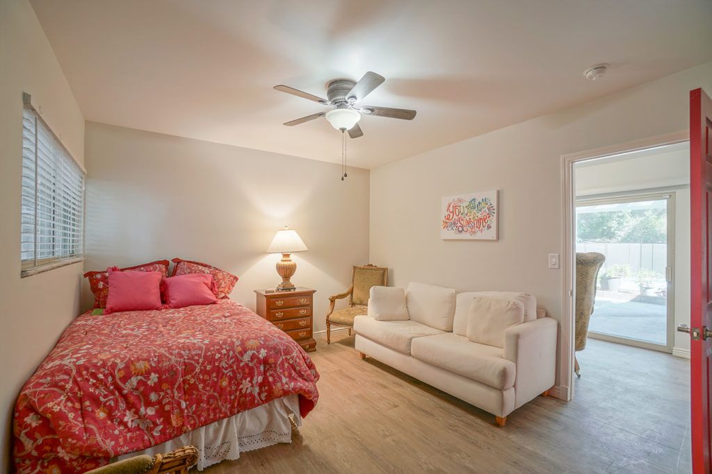 Cozy bedroom with a bed, sofa, and ceiling fan.