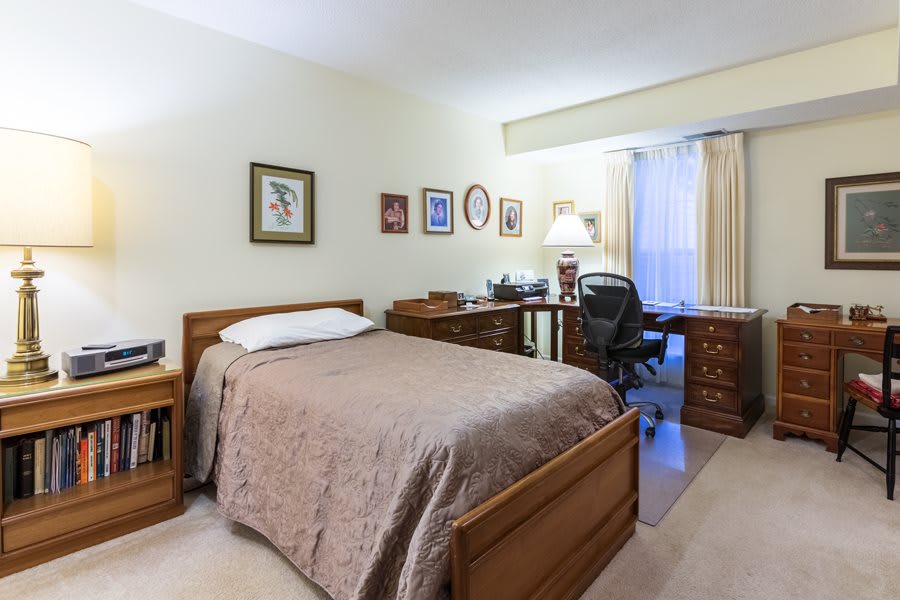 A cozy bedroom with a single bed, desk, and decor on the walls.