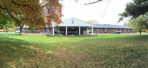 A spacious residential home with a welcoming porch surrounded by a lush green lawn.