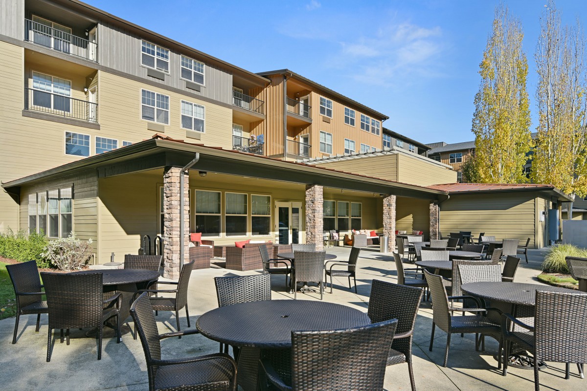 Outdoor patio area with tables and chairs in front of a residential building.