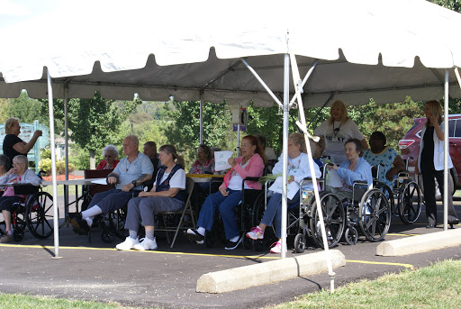 A group of elderly individuals enjoying a community event under a tent.