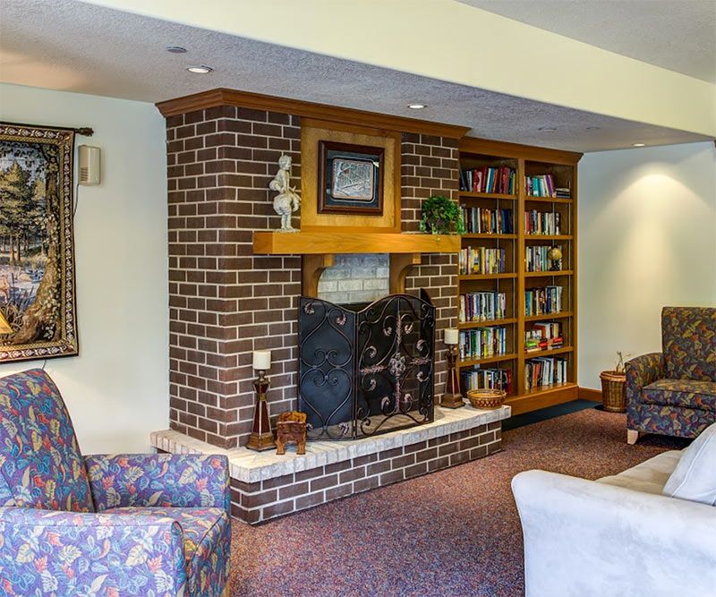 A cozy living room with a brick fireplace, bookshelves, and comfortable seating.