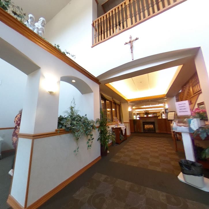 The interior of a church featuring a hallway with decorative elements and a visible cross.