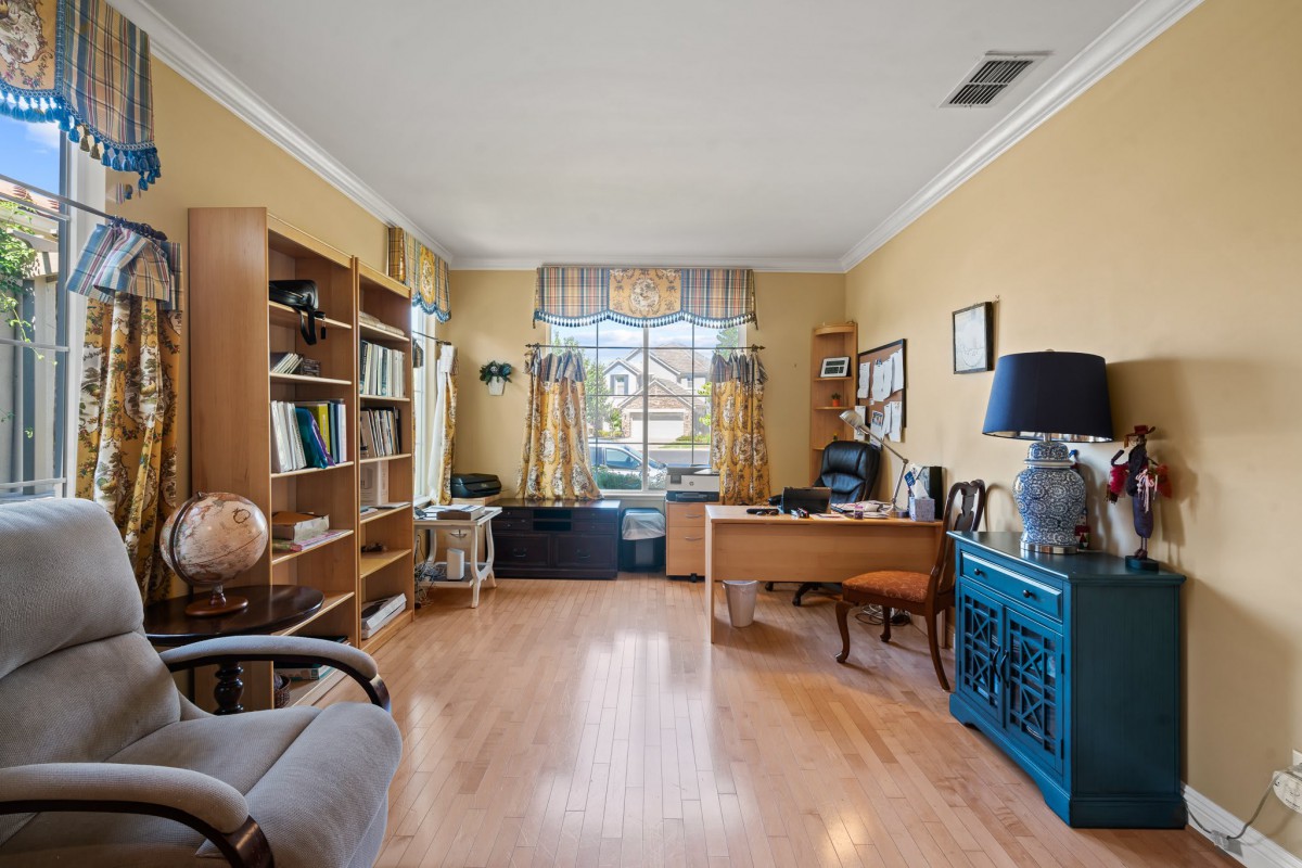 A spacious home office with bookshelves, a desk, and a large window allowing natural light.