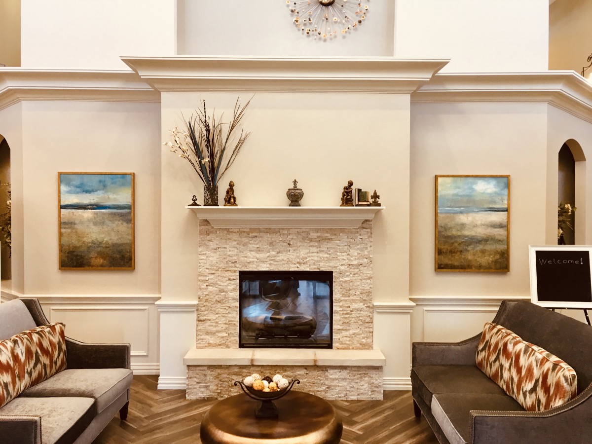 A modern living room with a central fireplace, elegant artwork, and stylish furnishings.