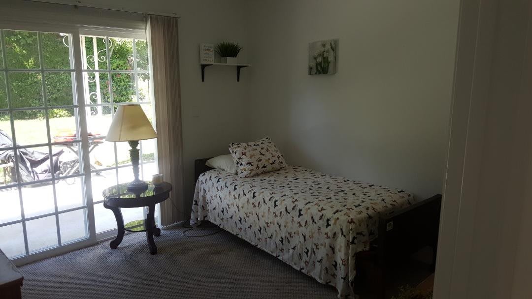 A cozy bedroom with a single bed, lamp, and window.