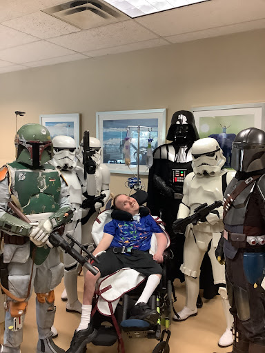 A group of Star Wars characters visiting a fan in a hospital, spreading joy and creativity.