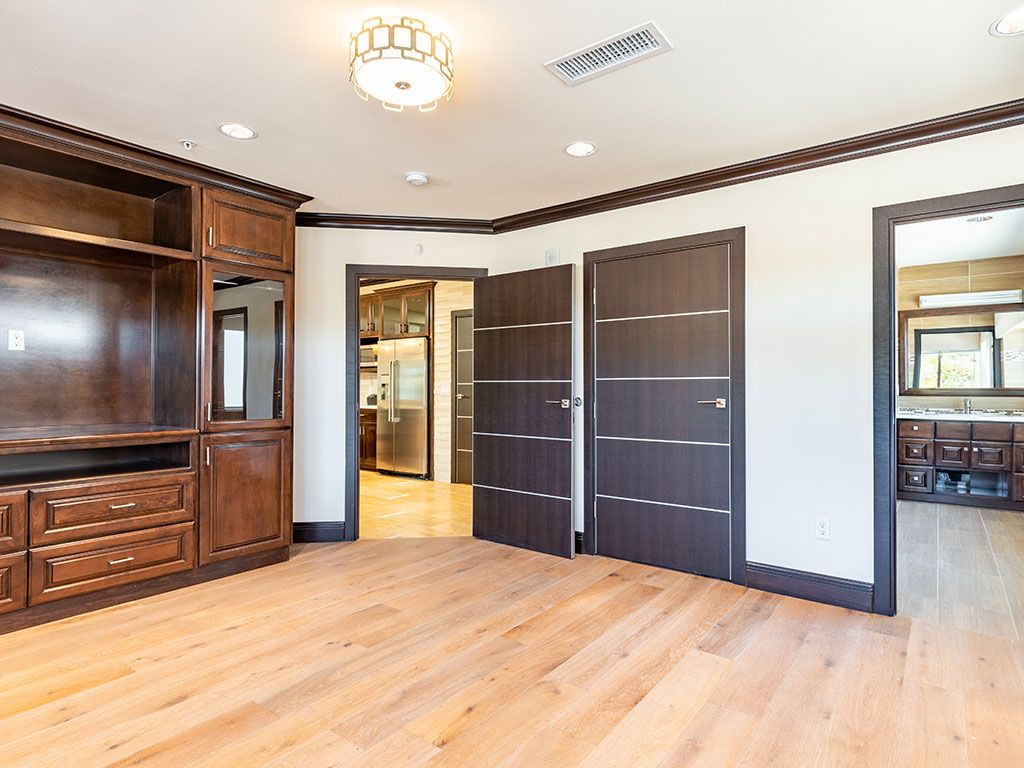 An empty room featuring hardwood flooring, built-in wooden shelves, and a modern ceiling light.