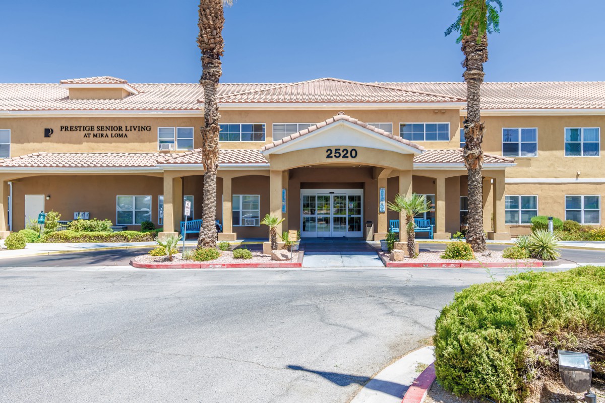 A sunny day view of a two-story building with palm trees framing the entrance.