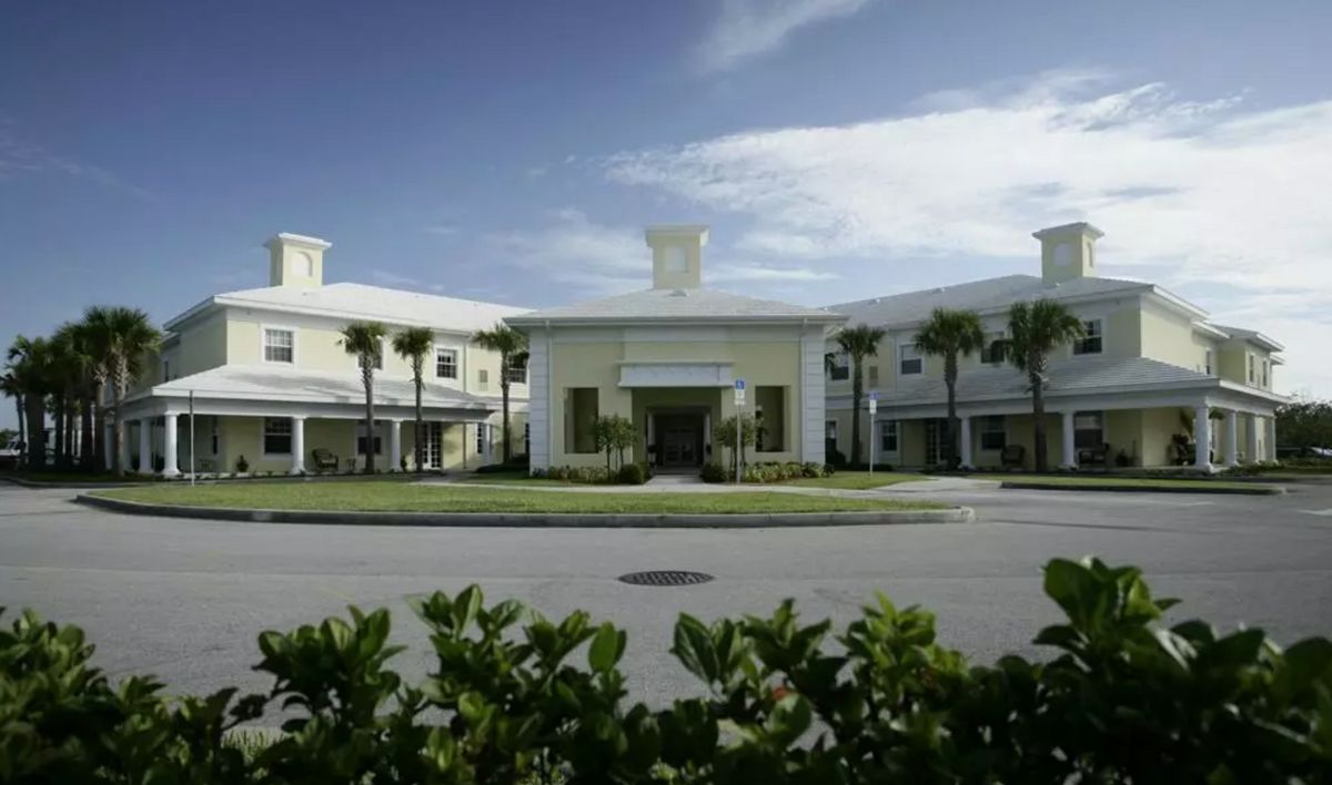 A modern building with palm trees under a clear sky.