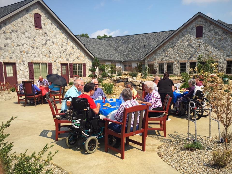 A group of seniors enjoying an outdoor gathering in a courtyard with stone buildings.