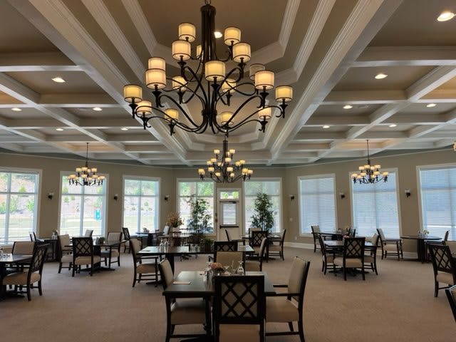 A spacious dining area with elegant chandeliers and neatly arranged tables and chairs.