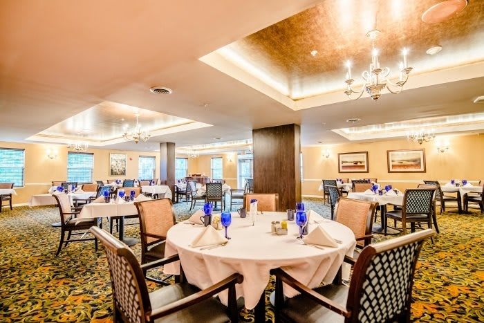 A spacious and elegantly designed dining area with well-arranged tables and warm lighting.