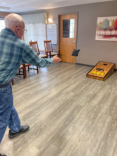 An elderly man enjoying a game of cornhole indoors.