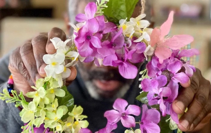 A man holding a vibrant floral arrangement with purple and white flowers.