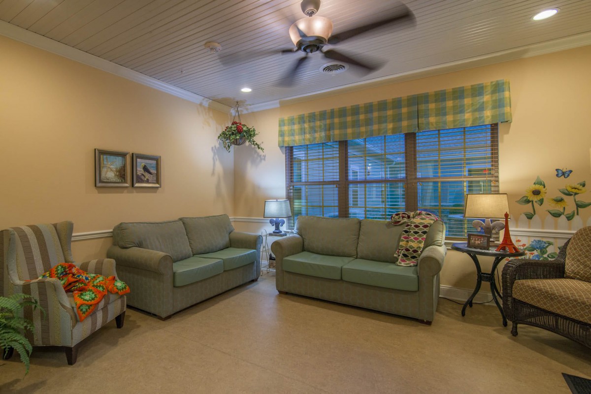 A cozy living room with two sofas, a ceiling fan, and warm lighting.