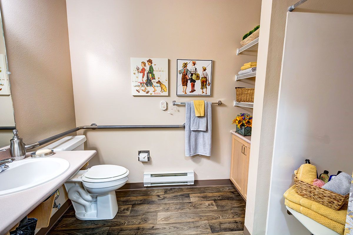 A neatly organized bathroom featuring wall art, a towel rack, and shelves with towels and decor.