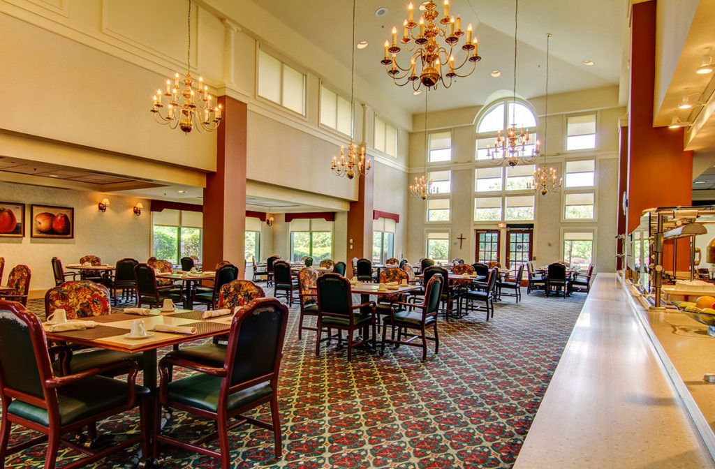 An elegant dining room with chandeliers and a carpeted floor.