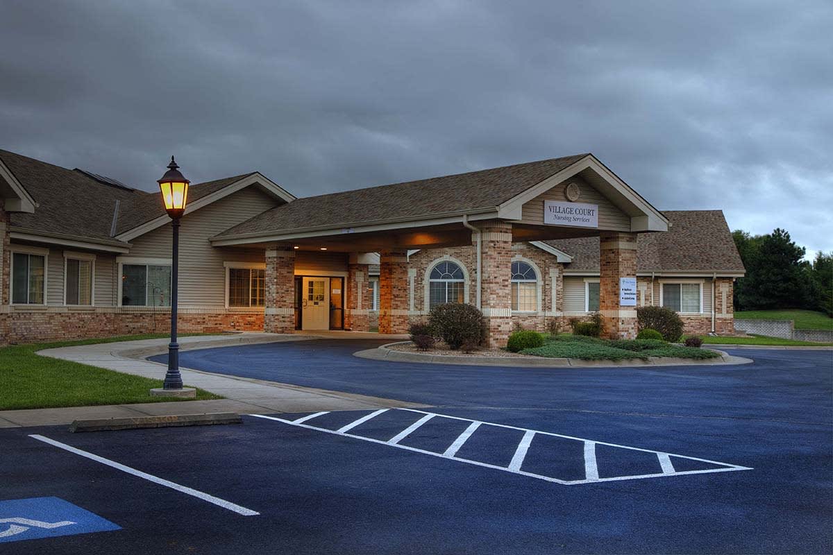 A building with a parking lot under a cloudy sky.