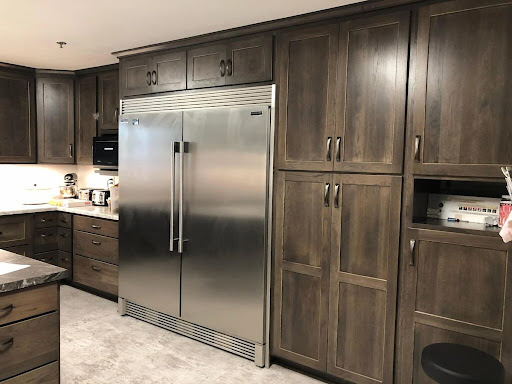 A contemporary kitchen featuring a stainless steel refrigerator and dark wooden cabinetry.
