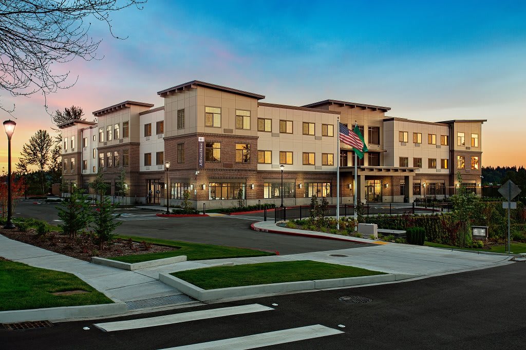 A modern commercial building with landscaped surroundings and flags at the entrance.