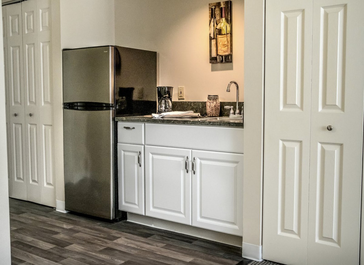 Compact kitchen area with a mini fridge, white cabinets, and countertop appliances.