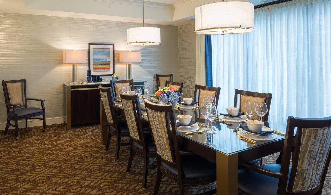 An elegantly set dining room with a large table, chairs, and ambient lighting.