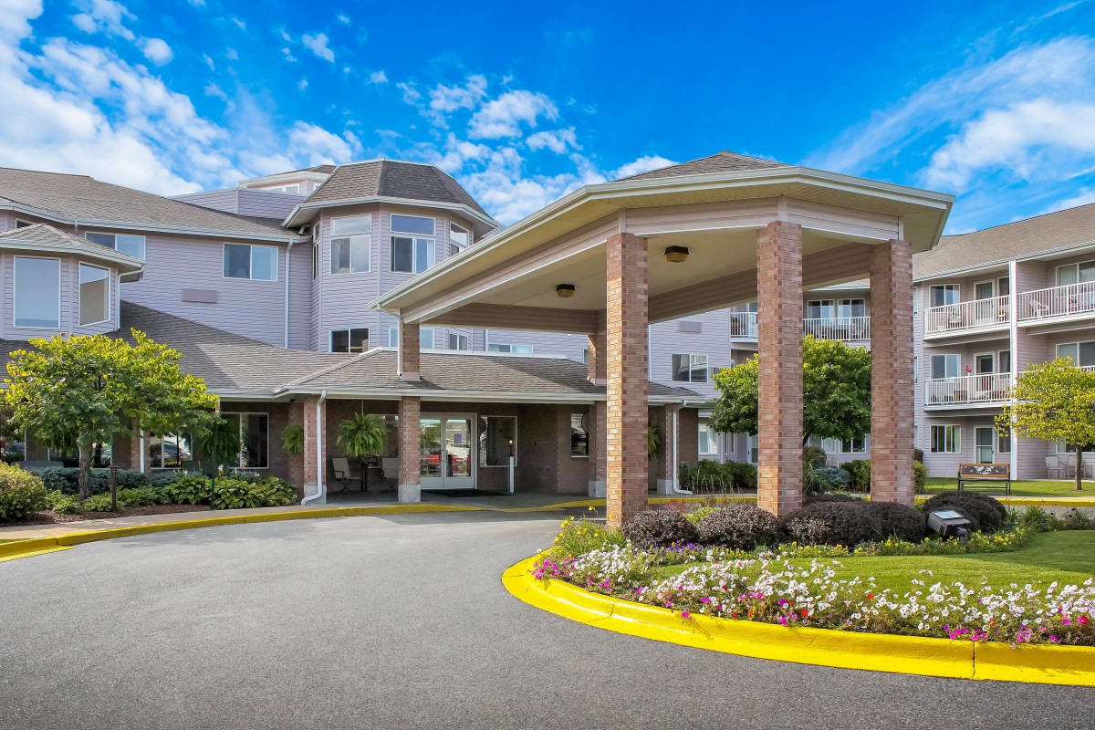 A residential building with a welcoming entrance and landscaped surroundings under a partly cloudy sky.