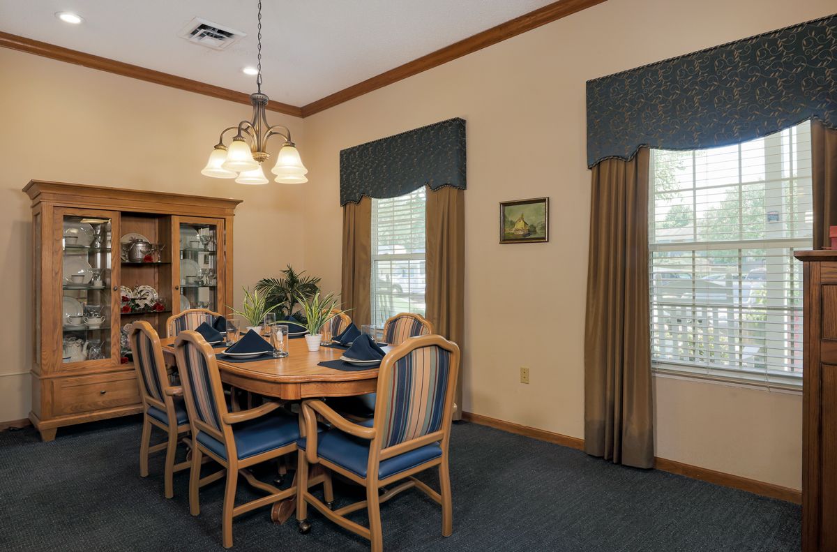 A neatly arranged dining room with a wooden table and chairs, illuminated by a chandelier.