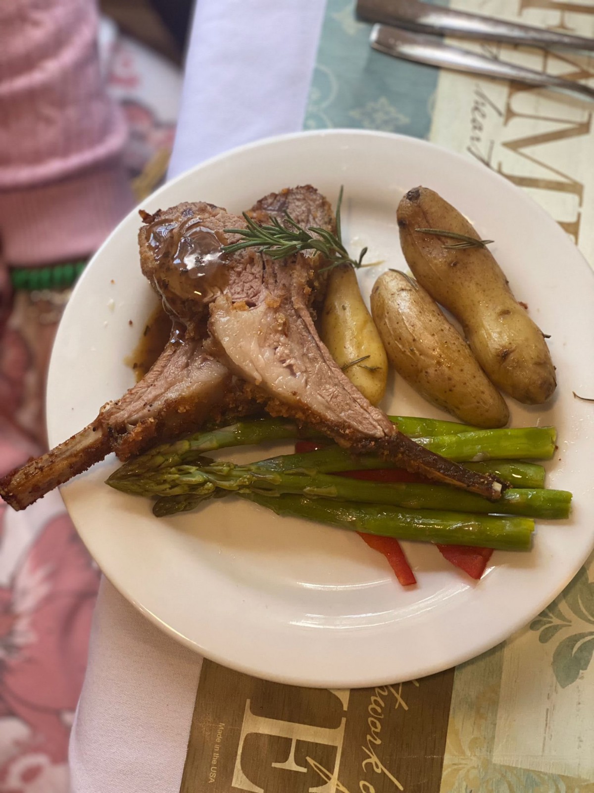 A plate of lamb chops served with fingerling potatoes and asparagus.