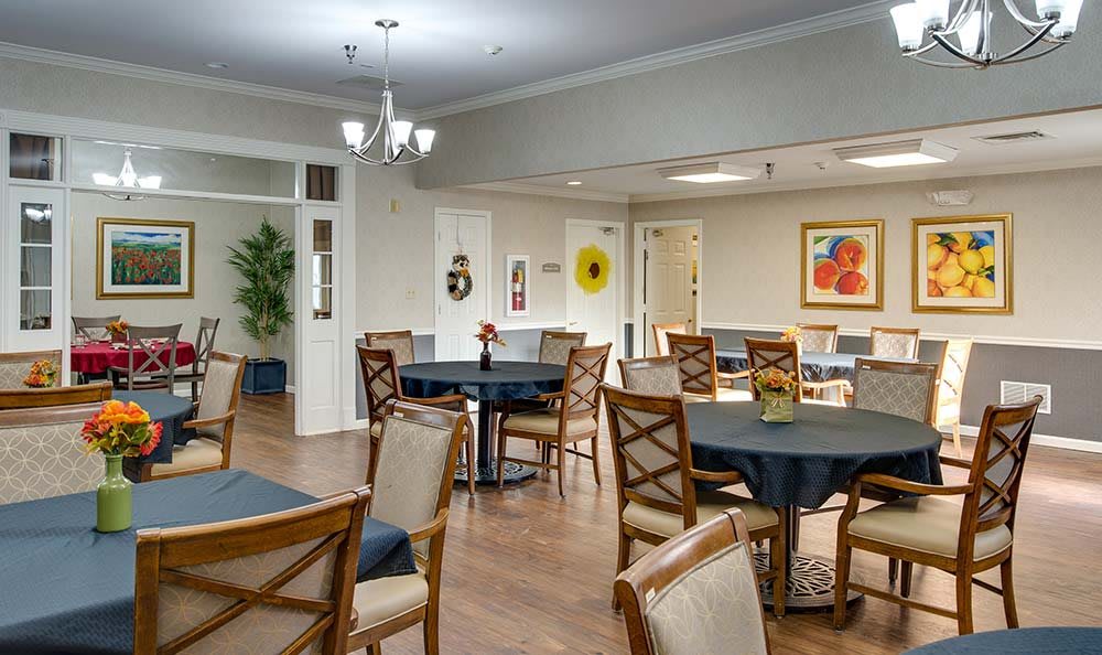 A well-furnished dining area with multiple tables and chairs, decorative artwork, and soft lighting.