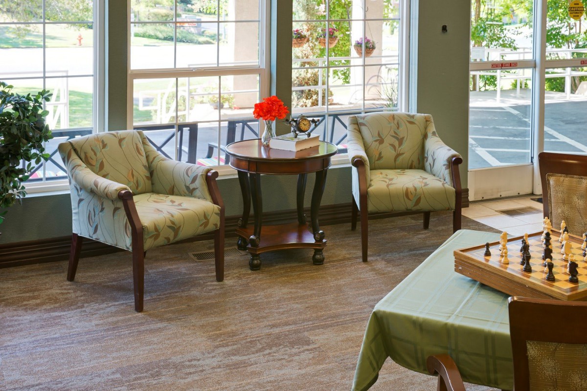 A cozy living room setup with two armchairs and a small wooden table next to large windows.