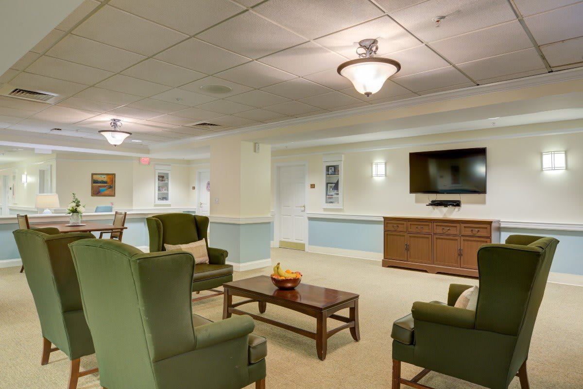 A cozy seating area with comfortable chairs, a television, and warm lighting.