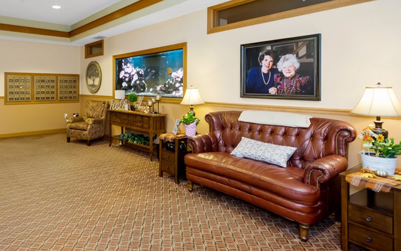 A cozy living room with a leather sofa, an aquarium, and decorative wall art.