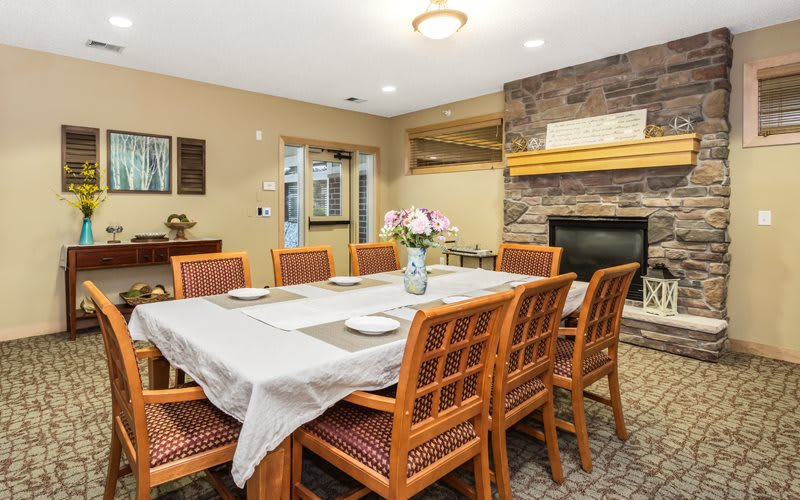 A cozy dining room with a well-set table and a stone fireplace.