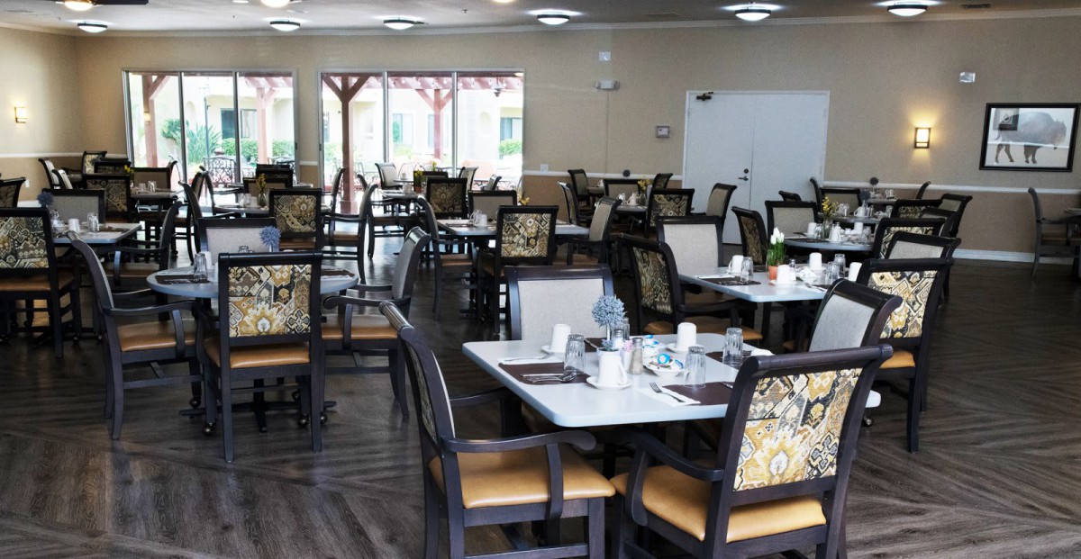 An empty restaurant dining room with neatly arranged tables and chairs.