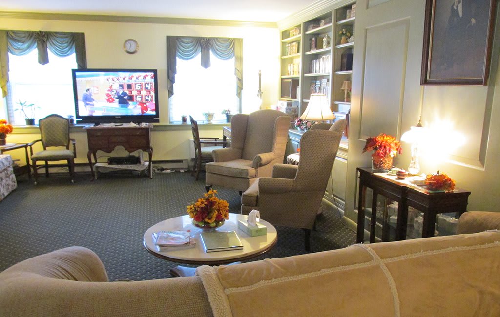 A cozy living room with armchairs, a television, and built-in bookshelves.