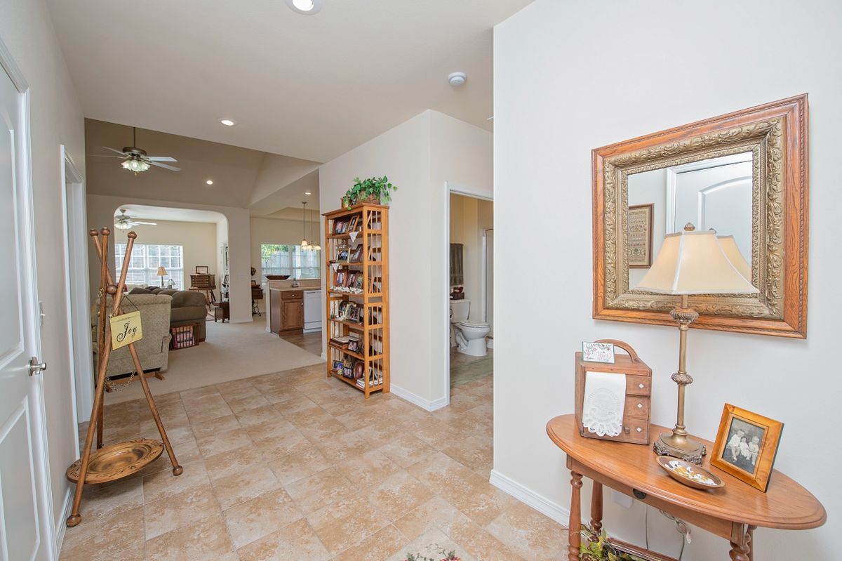 A cozy home interior featuring a hallway leading to a living room, with decorative elements like a mirror, lamp, and shelf.
