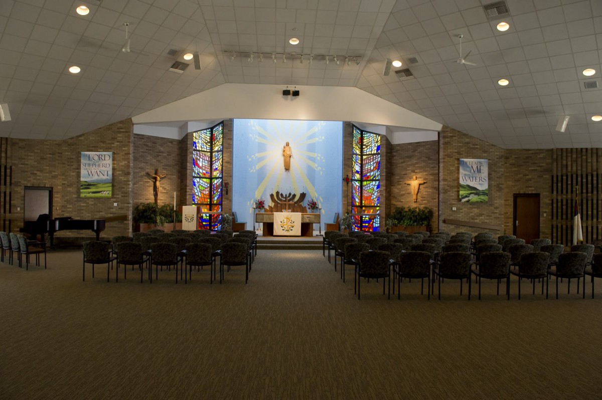 Interior of a church featuring an altar and stained glass windows.
