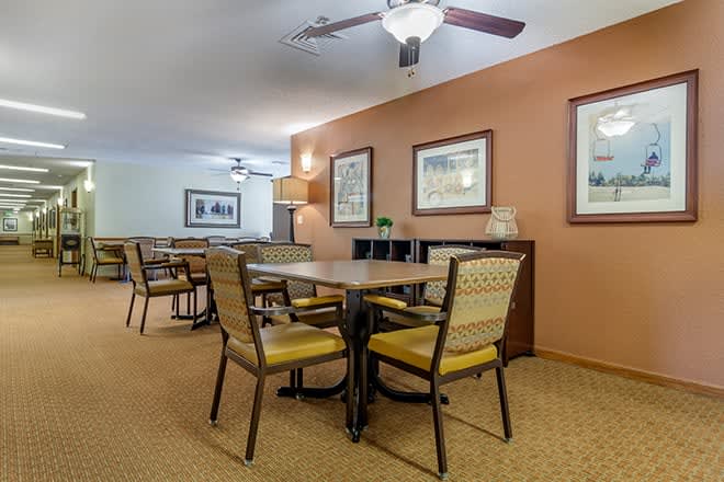 A cozy dining area with tables and chairs, decorated with artwork and warm-colored walls.